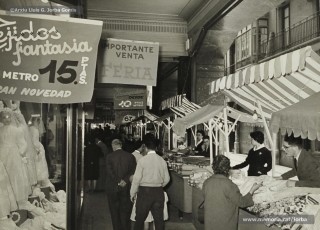 (6/12) Maig de1959. Paradetes amb tot d’ofertes de fira que Magatzems Jorba muntava als porxos que donaven al carrer Nou i al xamfrà de la Plaça de Sant Domènec.