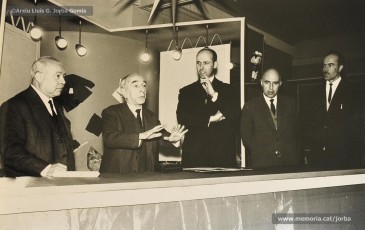 (2/14) Any 1965. Homenatge a Lluis Torra Pujol (1900-1968) amb motiu de la seva jubilació. Aquest empleat havia treballat 50 anys a Can Jorba, a l’administració de la secció de queviures. L’acompanyen Pere Jorba Puigsubirà, a la seva dreta, i Lluís G. Jorba Gomis, a la seva esquerra. Pere Jorba Puigsubirà féu el parlament en nom de l’empresa.
