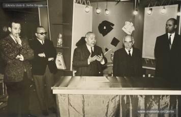 (6/14) Any 1965. Homenatge a Lluis Torra Pujol (1900-1968) amb motiu de la seva jubilació. Aquest empleat havia treballat 50 anys a Can Jorba, a l’administració de la secció de queviures. L’acompanyen Pere Jorba Puigsubirà, a la seva dreta, i Lluís G. Jorba Gomis, a la seva esquerra. Pere Jorba Puigsubirà féu el parlament en nom de l’empresa.