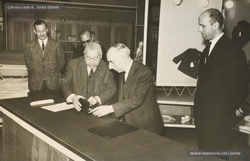 (10/14) Any 1965. Homenatge a Lluis Torra Pujol (1900-1968) amb motiu de la seva jubilació. Aquest empleat havia treballat 50 anys a Can Jorba, a l’administració de la secció de queviures. L’acompanyen Pere Jorba Puigsubirà, a la seva dreta, i Lluís G. Jorba Gomis, a la seva esquerra. Pere Jorba Puigsubirà féu el parlament en nom de l’empresa.