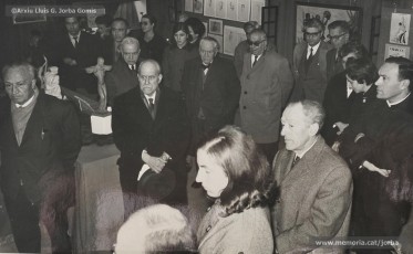 (3/4) 20/2/1969. Presentació de l’exposició d’homenatge a Lluís Uró a càrrec de Pere Jorba Puigsubirà. A la seva esquerra, hi ha el dibuixant Joan Vilanova i, a la seva dreta, el músic Josep Padró i Antoni Fernàndez. L’exposició es feia a la 5ª planta de Cal Jorba.