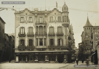 (1/2) Any 1933. Edifici dels Magatzems Jorba. S’hi anuncia el preu fix per als articles, una innovació introduïda al 1904, a Manresa, pels Magatzems Gras i que els Magatzems Jorba adoptaren un any després, en traslladar el centre de l’empresa a aquest edifici. Així s’eliminava el sistema tradicional del regateig o dels preus fets com un capmàs. Joan Jorba Rius també va introduir el sistema mètric decimal per mesurar les teles, abandonant les mesures tradicionals en canes.