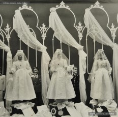 (2/2) Fira de l’Ascensió de 1959. Aparador amb tot de teles i els premis d’un sorteig entre la clientela: un televisor, un aparell de ràdio i nou despertadors; i aparador amb vestits de la primera comunió per a nena.