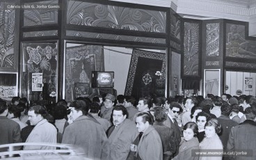 (10/11) 15/2/1959. A l’any 1959 s’havien inaugurat els estudis de Miramar, a Barcelona, cosa que permetia la recepció de les emissions de televisió a Catalunya. Podem veure una multitud de persones que estan mirant encuriosides els aparadors de Cal Jorba per veure el partit entre el Reial Madrid i el FC Barcelona. Magatzems Jorba feia un sorteig de 13 premis, el primer dels quals era un aparell de televisió, entre els seus clients. Els aparells de televisió eren un producte de gran luxe (valien unes 30.000 ptes., el que cobrava un mestre en un any i mig de treball) que poques famílies es podien permetre adquirir.