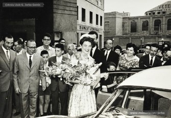 (7/8) 5/6/1960. Foto promocional de Sandra Lee Jennings, miss California 1959 i Maid of Cotton als Estats Units d’Amèrica. Arribada de la carrossa de Miss Cotó a Can Jorba per la Muralla de Sant Domènec. A l’arribada a Cal Jorba és rebuda per Magí Carrió Plans, gerent de Magatzems Jorba, Ramon Brunet, cap de la secció de joieria i bijuteria, i Quirze Font, del Consell d’Administració.