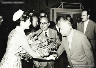(8/8) 5/6/1960. Foto promocional de Sandra Lee Jennings, miss California 1959 i Maid of Cotton als Estats Units d’Amèrica. Arribada de la carrossa de Miss Cotó a Can Jorba per la Muralla de Sant Domènec. A l’arribada a Cal Jorba és rebuda per Magí Carrió Plans, gerent de Magatzems Jorba, Ramon Brunet, cap de la secció de joieria i bijuteria, i Quirze Font, del Consell d’Administració.