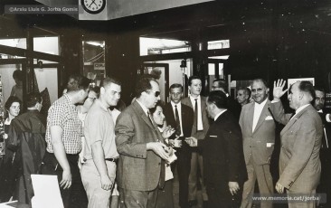 (2/9) Any 1965. Anunci d’un obsequi per a tots els turistes que visitessin Can Jorba i visita d’un grup de turistes convidats; alguns d’ells es posen la típica barretina. Aquesta campanya formava part de la gran promoció turistica que s’havia començat a fer a Catalunya en aquesta època.