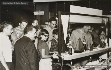 (3/9) Any 1965. Anunci d’un obsequi per a tots els turistes que visitessin Can Jorba i visita d’un grup de turistes convidats; alguns d’ells es posen la típica barretina. Aquesta campanya formava part de la gran promoció turistica que s’havia començat a fer a Catalunya en aquesta època.