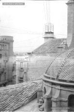 Anys 20 del segle XX. Fotografia feta des dels magatzems Jorba on es veu la cúpula de la capella del Roser, l'edifici de ca la Buresa, i l'edifici de l'antiga Telefònica, on hi ha una torre de la qual surten tota una sèrie de cables telefònics.