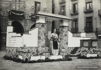 (1/3) 21/10/1951. La pubilla de Manresa a la Plaça Major. A cada banda del ninot, que representava l’entrada i el pati d’una masia catalana, hi havia els versos de la “Cançó de la Pubilla”, escrita pel farmacèutic i músic manresà Josep M. Mestre Miret (1918-2002). A la tarda es va fer una xocolatada, repartiment de flabiols i elevació de bombes japoneses per la canalla; finalment, a les 6, es va encendre el ninot i es va fer una audició de sardanes.