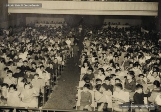 (11/19) Octubre de 1966. Acte de fi de curs 1965-66 de les sessions de cinema infantil. Lliurament del record d’assistència per Pere Jorba Puigsubirà, president del Consell d’Administració de Magatzems Jorba, Dolors Ponsà, empleada de Cal Jorba, i el pare Ferran Torra Sisquella SJ (1893-1990), director de les Congregacions Marianes.