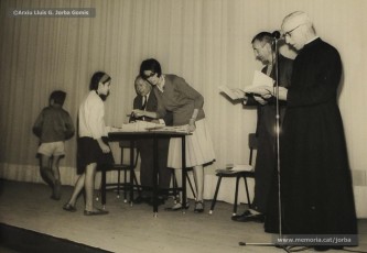 (10/19) Octubre de 1966. Acte de fi de curs 1965-66 de les sessions de cinema infantil. Lliurament del record d’assistència per Pere Jorba Puigsubirà, president del Consell d’Administració de Magatzems Jorba, Dolors Ponsà, empleada de Cal Jorba, i el pare Ferran Torra Sisquella SJ (1893-1990), director de les Congregacions Marianes.