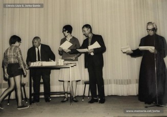 (16/19) Octubre de 1966. Acte de fi de curs 1965-66 de les sessions de cinema infantil. Lliurament del record d’assistència per Pere Jorba Puigsubirà, president del Consell d’Administració de Magatzems Jorba, Dolors Ponsà, empleada de Cal Jorba, i el pare Ferran Torra Sisquella SJ (1893-1990), director de les Congregacions Marianes.