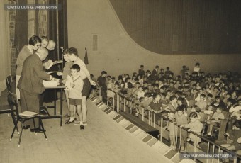 (18/19) Octubre de 1966. Acte de fi de curs 1965-66 de les sessions de cinema infantil. Lliurament del record d’assistència per Pere Jorba Puigsubirà, president del Consell d’Administració de Magatzems Jorba, Dolors Ponsà, empleada de Cal Jorba, i el pare Ferran Torra Sisquella SJ (1893-1990), director de les Congregacions Marianes.