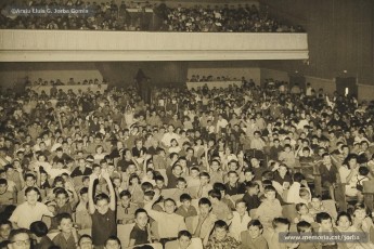 (19/19) Octubre de 1966. Acte de fi de curs 1965-66 de les sessions de cinema infantil. Lliurament del record d’assistència per Pere Jorba Puigsubirà, president del Consell d’Administració de Magatzems Jorba, Dolors Ponsà, empleada de Cal Jorba, i el pare Ferran Torra Sisquella SJ (1893-1990), director de les Congregacions Marianes.