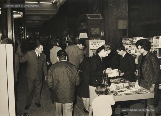 (12/12) Dia del Llibre any 1967. Parades de llibres amb motiu de la diada als porxos de Magatzems Jorba. S’hi veuen les parades de les llibreries Símbol, Perramon