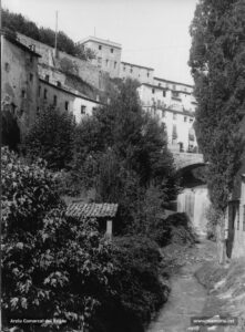 Perspectiva del pontarró de Sant Marc, construït l'any 1587, i del salt dels Gossos. L'any 1925, un redactor del Diario de Avisos qualificava aquest indret com el "barri xinès" de la ciutat: «Encara que no ho sembli, parlem de "Les Fontetes" i dels carrerons infectes que circumden aquell torrentot, les aigües tèrboles del qual s'escorren descovertes entre un llit de runa i escorrialles que hi aboquen els tètrics casalots de llurs voreres (...) Aquí, una cascata feta mestívolament, surt d'un forat misteriós, i la remos engresca la roba estesa a les aixides (...) Allà un pont de la pagesia molt evocatiu. Hom palesa la imatgeria d'un pessebre, abdhuc, d'un pessebre animat: molt a la vora unes dones hi renten la roba amb sengles cops de picador. Tot és tan vell, tan massís, que hom enyora el no poder trobar  un indici que li depare la coneixentsa de la data en què fou construït. Es de l'època neolítica, ciclòpea, o de l'edat mitjana? No és possible el jeroglífic de finestres, balcons, aixides i teulades amb giravoltes de muntanyes runes. Per tot enlleïments, fetors, porqueries... igual que deu, vint, trenta anys enrera! (...) Els cantonots de sota el Parc, el pont que mena a la Cova, batejats popularment amb els noms "Els Corrals" i "El Salt dels Gossos" fan joc amb "Les Fontetes". Tan atractívols com el torrent, pugen i baixen, es torcen i cargolen (...)».
Procedència: Arxiu Jaume Pons i Agulló.