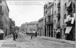 La carretera de Cardona en una fotografia de començaments del segle XX. Juntament amb la carretera de Vic, aquest fou un dels eixos de creixement urbanístic de la ciutat. Aquest vial experimentà en el decurs del darrer quart de segle un intens procés d'edificació que donà com a resultat la instal·lació de comerços a l'engròs, d'activitats tèxtils i de tallers de diversa índole que treballaven per a les fàbriques de teixits. En aquesta imatge apareix, a tall d'exemple, la fàbrica de Pere Perera, a la dreta
Procedència: Arxiu Comarcal del Bages