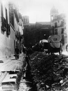 La canalització de l'aigua potable al començament de la carretera de Cardona, just al davant del carrer de Jaume I. Al fons, l'església de Sant Pere Màrtir. A la dreta, la casa Viñas, edificada al xamfrà entre la Muralla i el carrer de Jaume I. La casa Viñas va ser feta construir pels volts de l'any 1920 pel fabricant Lluís Viñas i Guix. 
Procedència: Col·lecció Josep Huerta i Muntalà