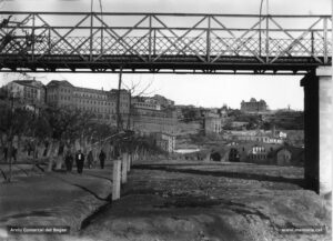 El passeig del Riu vist des de sota la passarel·la de ferro, cap als anys vint del segle passat. Al fons, el Pont Vell i la fàbrica que duu el mateix nom. A l'horitzó més immediat, la Cova de Sant Ignasi i, enlairat, el convent de Santa Clara.
Procedència: Arxiu Comarcal del Bages