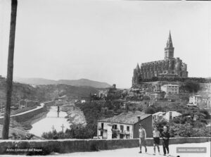 La Seu i el riu Cardener, vistos des de la Cova de Sant Ignasi. Tal com deia en to líric "L'Abella d'Or" l'any 1928, «per una banda, la pedra picada que toca, diríeu, al cel; per una altra banda, el riu que s'abraça amb la terra, tot reflectint el cel. Visió de Manresa, que té alguna cosa de grandiós i al mateix temps alguna cosa de manyac. D'allò que usualment s'anomenen "vistes" de poblacions, aquesta és sens dubte de les qui produeixen un efecte excel·lent de debò. I pensar que dins d'aquest recinte s'enclou tanta riquesa d'esperit i de treball, això fa que la visió sigui encara més comfortable» . En efecte, des d'aquest punt s'albiren, si bé llunyanes, la fàbrica de sedes Balcells, la fàbrica del pont de fusta i la fàbrica Viñas. Procedència: Arxiu Jaume Pons i Agulló