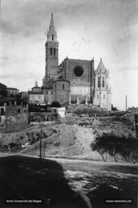 Instantània de la basílica de la Seu tal com era visible des de la plaça de la Reforma vers la meitat dels anys vint del segle passat. Cal observar que el nou pòrtic de la façana principal encara no ha estat construït, però sí que s'havia remodelat el campanar i s'havia aixecat el nou baptisteri. Al peu de la torre-campanar, es pot veure la capella dels favets o de la Puríssima. 
Procedència: Arxiu Francesc Villegas i Martínez