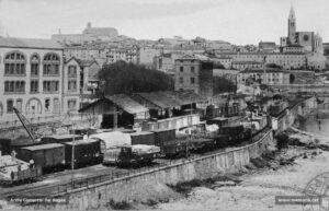 Vista de l'estació del passeig del Riu a l'inici dels anys vint, realitzada pel fotògraf Jaume Guixà amb ocasió del Xè congrés d'Esperanto celebrat a Manresa l'any 1923. Flanquejant l'estació, hi observem la farinera Albareda, projectada el 1909 per l'arquitecte Alexandre Soler i March, actualment encara en peu a la plaça del Mil·lenari de Catalunya i a continuació les dependències de la fàbrica de filats i teixits Roca. Al peu del riu, situats paral·lelament, el pont de pedra i la palanca de ferro, rere els quals es pot comprovar l'existència de la fàbrica del pont de fusta, on ara es troba l'edifici de l'antic Hotel Pere III.
Procedència: Arxiu Comarcal del Bages