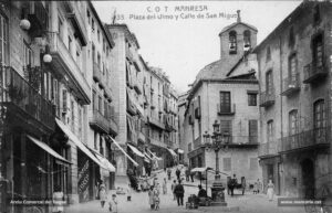 La Plana de l'Om en ple tràfec quotidià. L'Abella d'Or del 1928 parlava així d'aquesta plaça: «La plaça de l'Om és plaça escollida per la seva silueta elegant, per la seva discreció, pel seu aire distingit, pel seu nom que evoca un paisatge temperat i pacífic. La plaça de l'Om de Manresa, és un nom en certa manera representatiu; perquè àdhuc fora d'aquesta ciutat és conegut, per ésser d'aquest lloc d'on sortiren mantes vegades iniciatives que interessaven al món de la cultura.». Al fons a la dreta, l'església de Sant Miquel, enderrocada el 1936.
Procedència: Arxiu Comarcal del Bages.