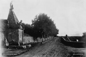 L'entrada a la ciutat de Manresa pel vessant sud-oest l'any 1904. En primer terme, la font de Neptú i, a la dreta, l'inici del Pont Nou que mena al cementiri municipal. Durant els anys vint del segle XX, de forma reiterada, la premsa diària denunciava la inexistència de voreres que permetessin als ciutadans manresans arribar còmodament al cementiri. De fet, la Junta del Cementiri cobrava un impost per aquest efecte.
Procedència: Arxiu Mas