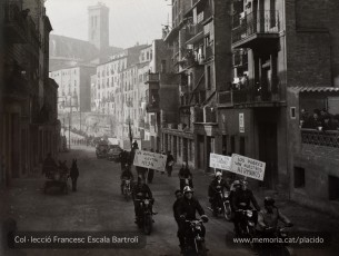 Motoristes a la Via de Sant Ignasi amb cartells al·lusius  a la caritat envers el pobres. (Col·lecció Francesc Escala Bartrolí)