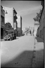 Vista del carrer de la Séquia el 1964, quan ja havia estat asfaltat. Al fons s’hi distingeixen les escales del pont que travessava per damunt la via del tren i la fàbrica on la Séquia passava al descobert.
