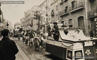 Desembre de 1961. Marià Homs contempla, des del balcó de casa seva (a dalt a la dreta), la desfilada de la caravana del príncep Assuan. Font: Arxiu Lluís G. Jorba Gomis.