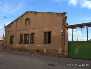 Aspecte actual de l’antiga fàbrica de l’Alcoholera Manresana, amb la seva gran xemeneia al fons. Actualment fa la funció de magatzem d’una empresa constructora.